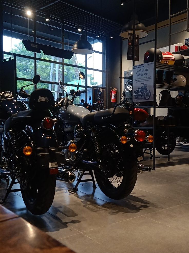 two motorcycles parked next to each other in front of a window with lots of windows