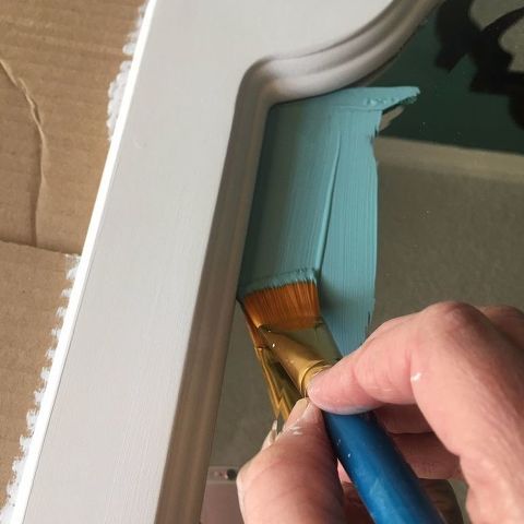 a person painting the trim on a wall with a paintbrush in their left hand