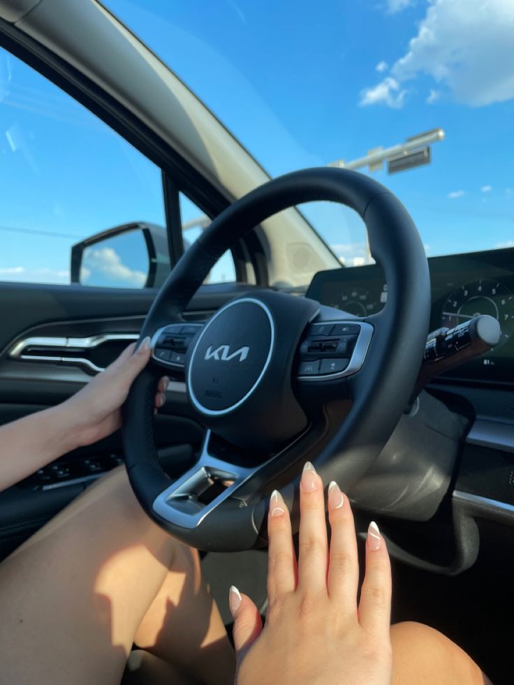 a woman driving a car with her hand on the steering wheel and hands on the dashboard