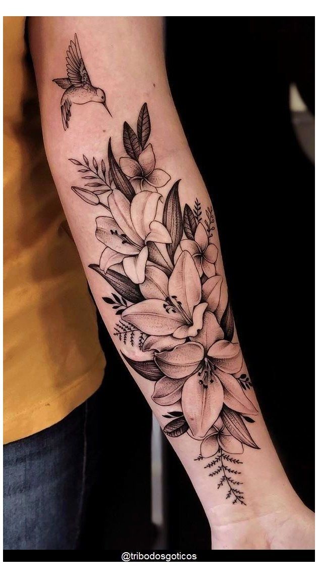 a woman's arm with flowers on it and a bird flying over the top