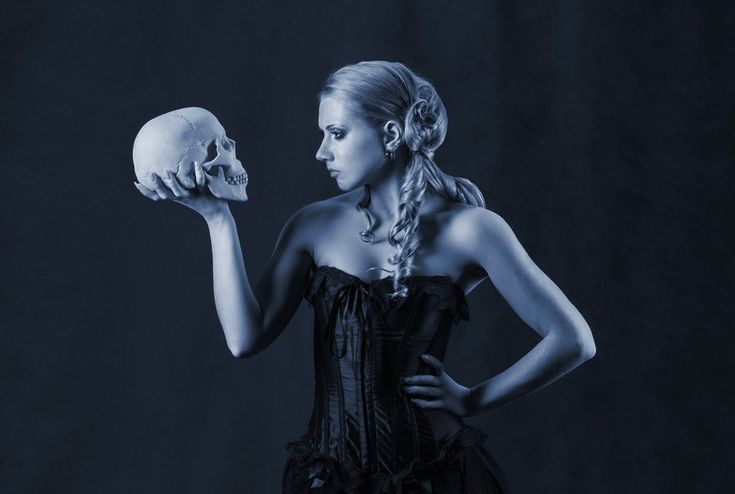 a woman in a corset holding a skull