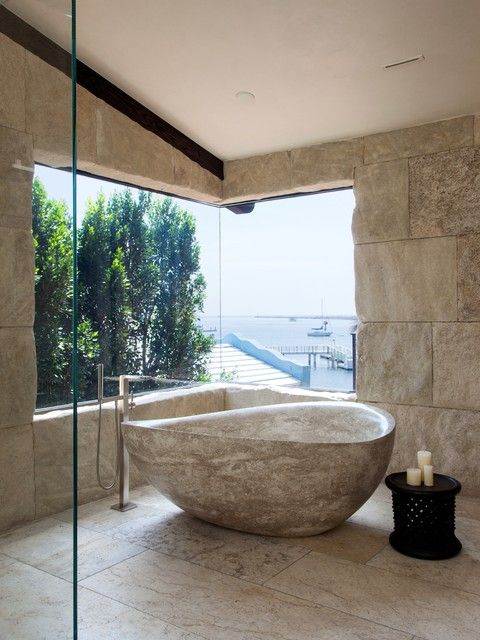 a large stone bathtub sitting in the middle of a bathroom next to a window