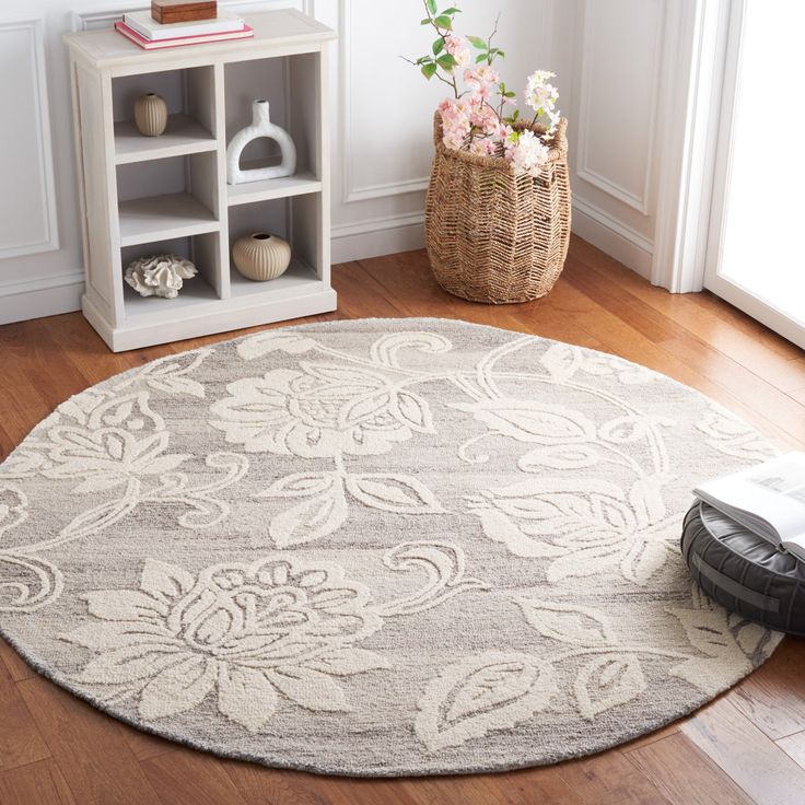 a white and gray area rug with flowers on it in front of a bookshelf