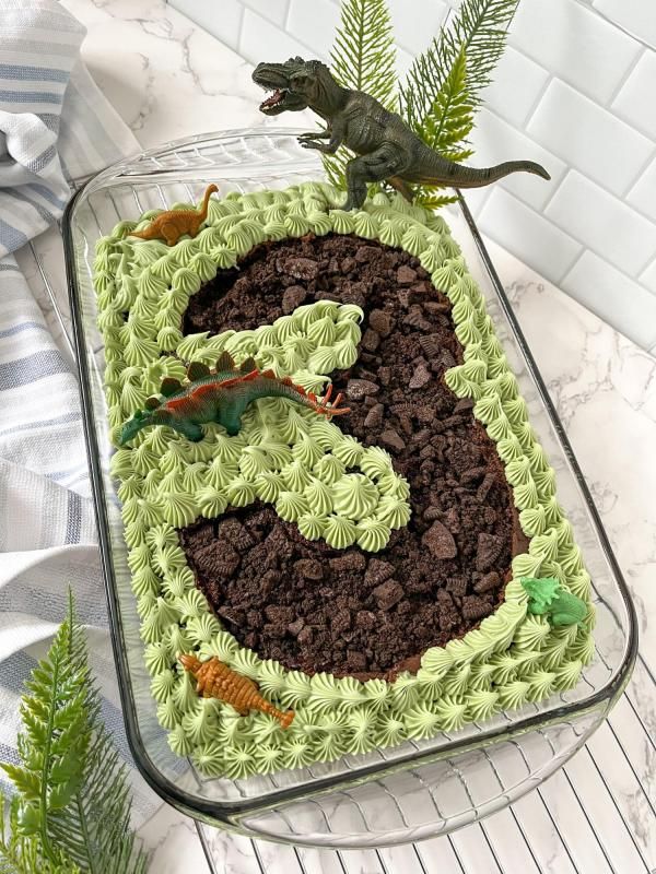 a dinosaur cake with green frosting and chocolate chips in the shape of number six