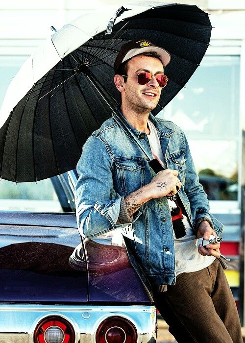 a man sitting on the hood of a car holding an open umbrella over his head