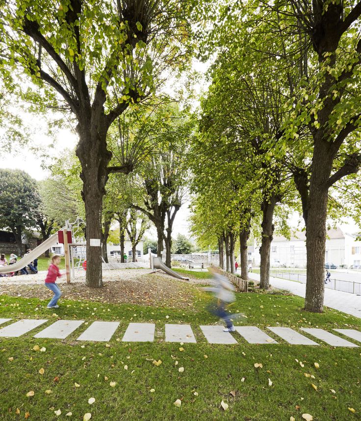 two children are playing in the park near some trees