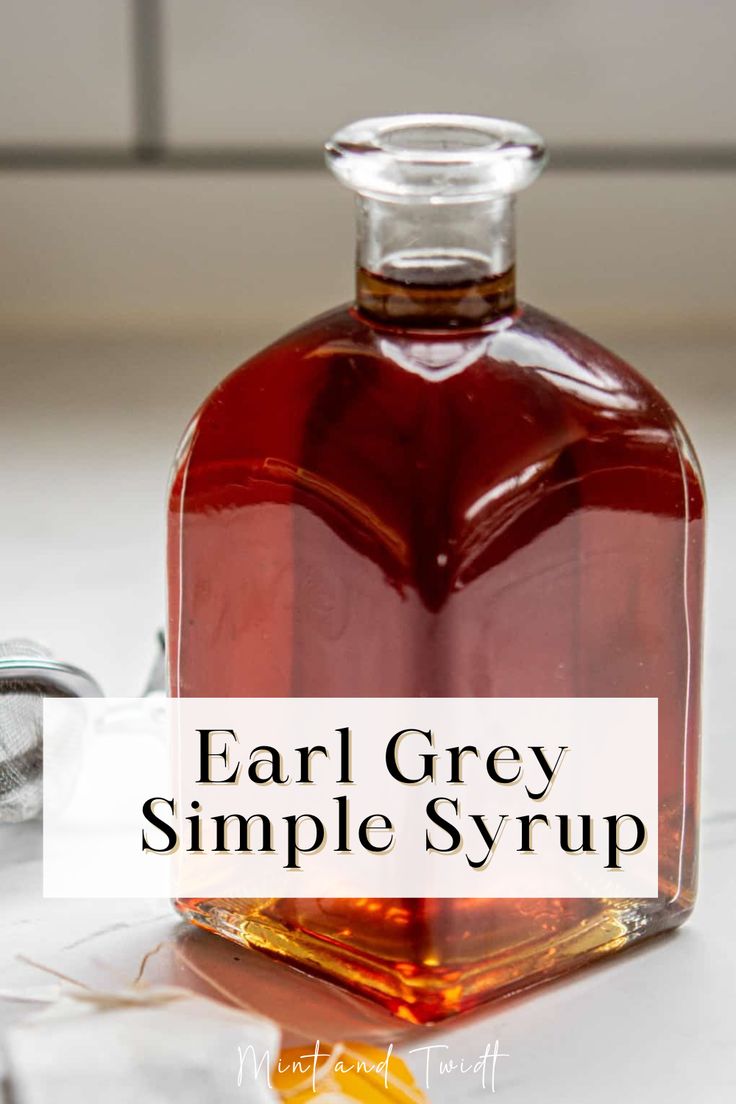 a bottle of gray simple syrup sitting on top of a counter next to an orange slice