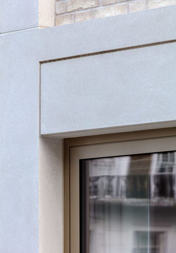 a black and white cat sitting on top of a window sill next to a building