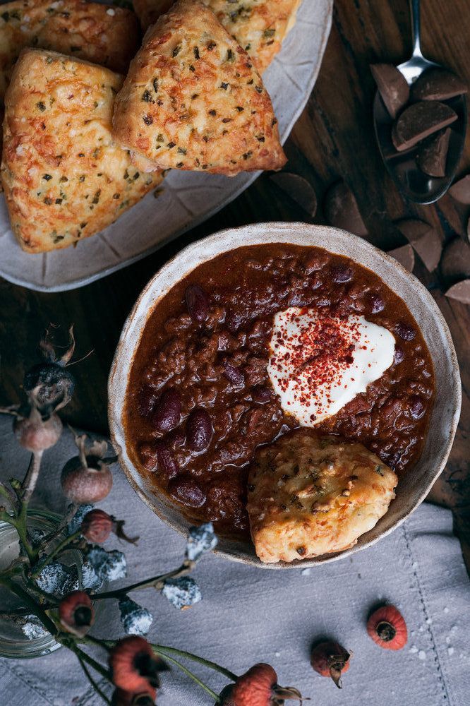 a bowl filled with chili and pastries on top of a table