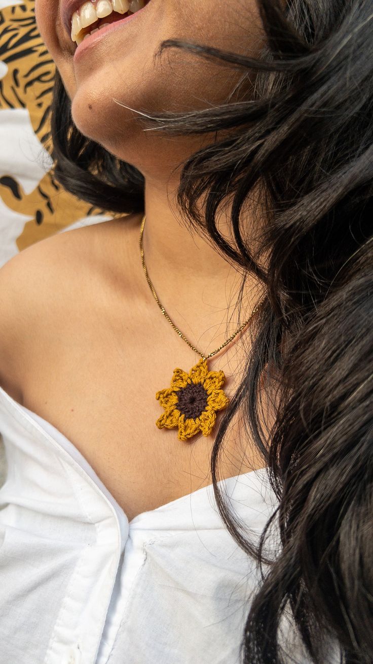 a close up of a woman wearing a necklace with a sunflower pendant on it