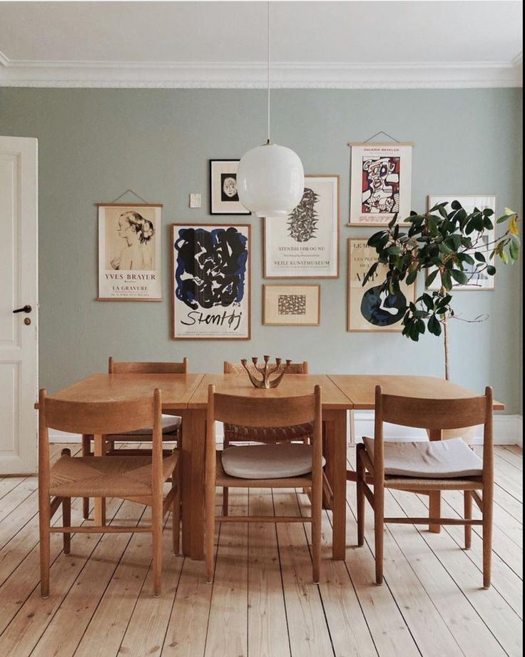 a dining room table with chairs and pictures on the wall