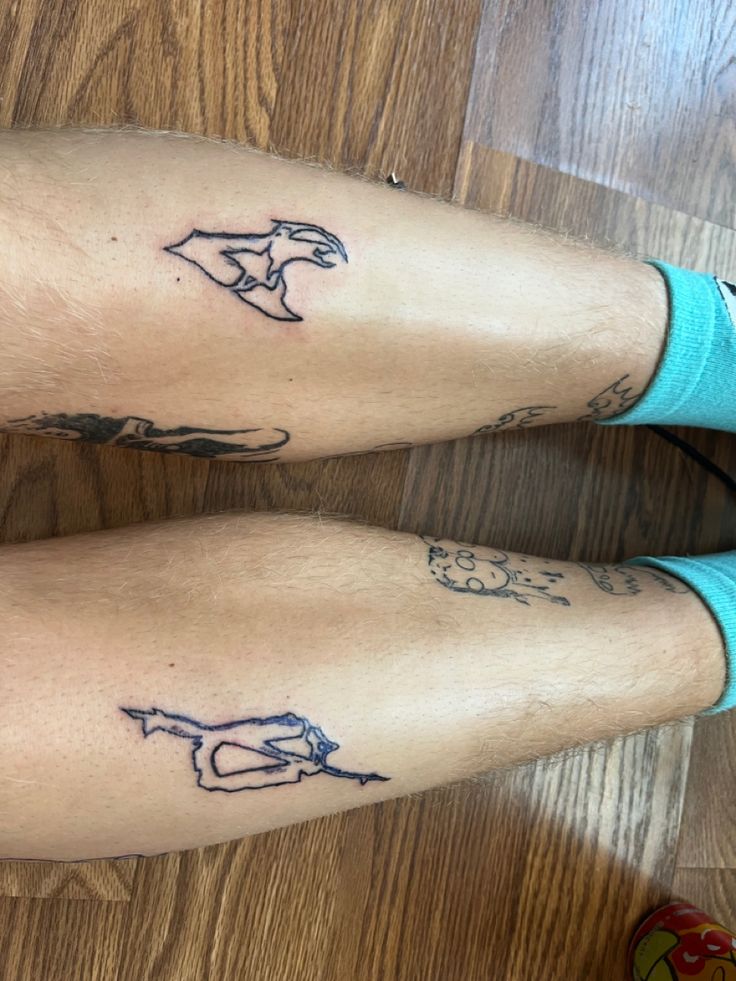 two people with tattoos on their legs sitting next to each other