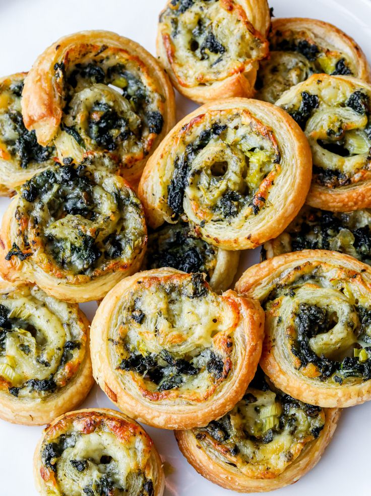 small pastries with spinach and cheese are on a white plate, ready to be eaten