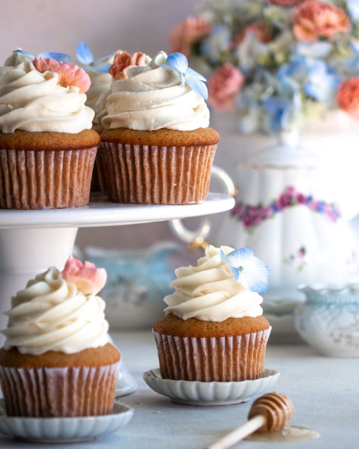 three cupcakes with white frosting sitting on top of a cake platter