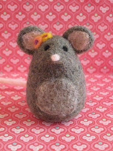 a small gray mouse sitting on top of a pink blanket