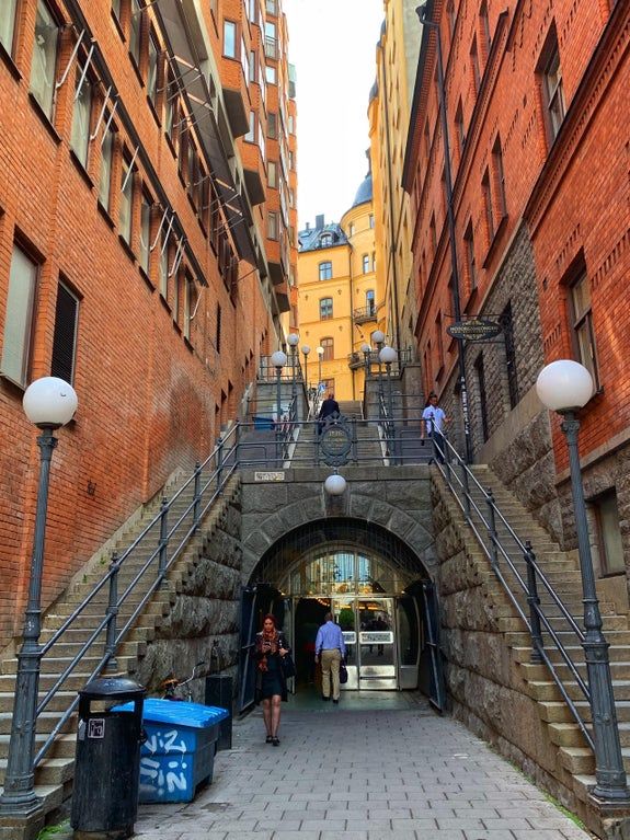 some people are walking up and down the stairs in an alleyway between two buildings