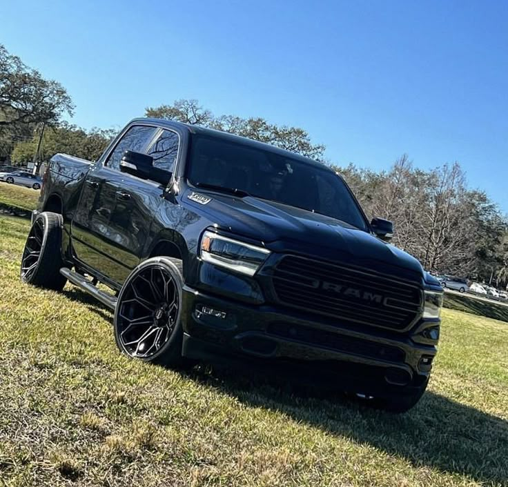 a black ram truck parked on top of a lush green field