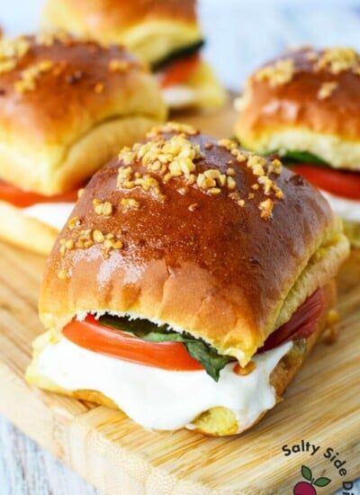 three sandwiches on a cutting board with cheese and tomatoes in the middle, topped with bread crumbs