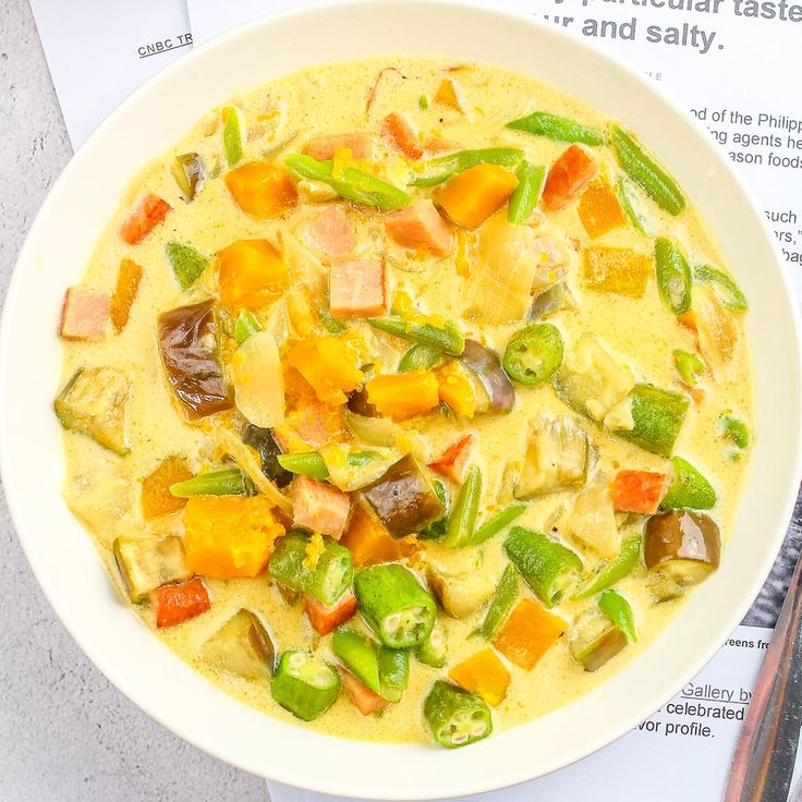 a white bowl filled with food on top of a table next to a piece of paper