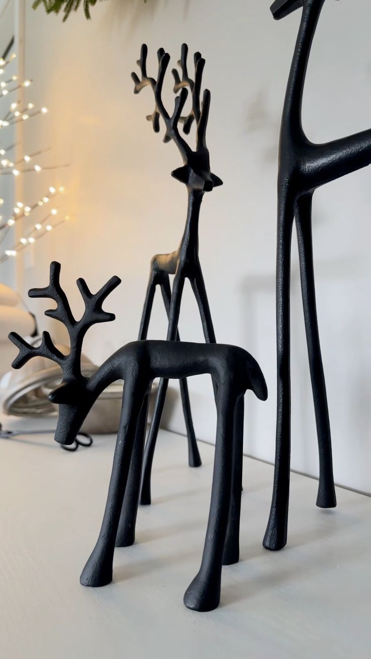 two black deer sculptures sitting on top of a white table next to a christmas tree