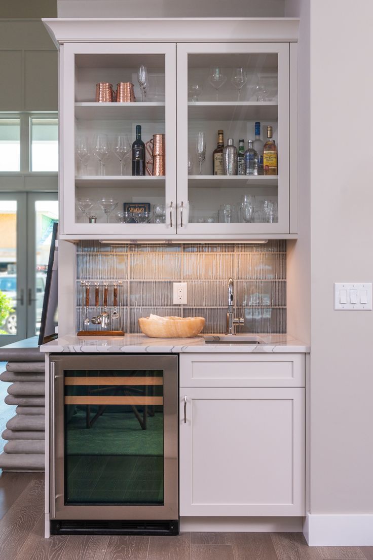 A wet bar adjacent to the kitchen features white cabinetry and a wine fridge. Wet Bar In Kitchen, Small Wet Bar Ideas, Beverage Station Kitchen, Kitchen Beverage Center, Small Home Bar Ideas, Small Wet Bar, White Cottage Kitchens, Bar In Kitchen, Inside Kitchen Cabinets