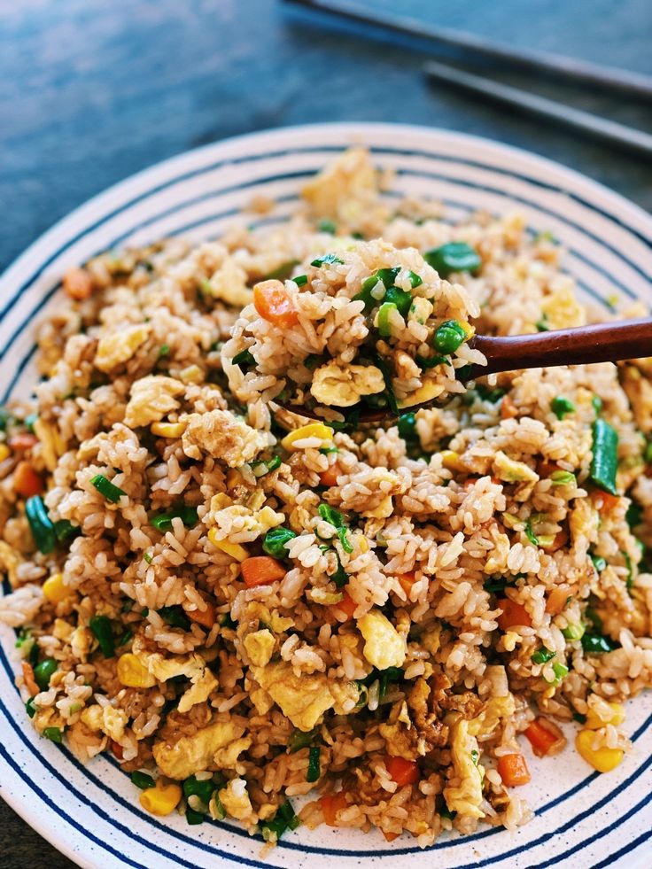 a white plate topped with fried rice and vegetables