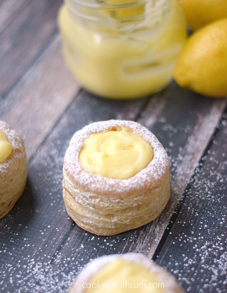 powdered sugar covered lemon cookies on a wooden table with lemons in the background