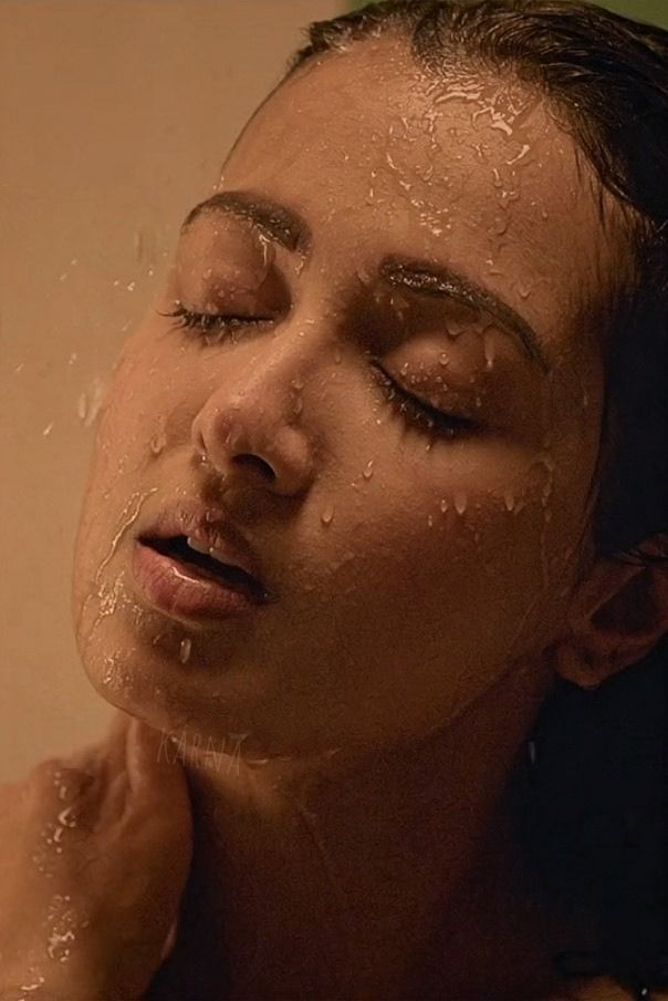 a woman is taking a shower with her eyes closed and water droplets all over her face