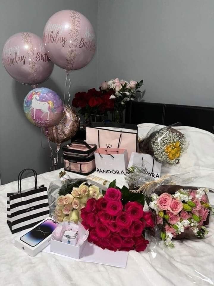 flowers and gifts on a bed with balloons