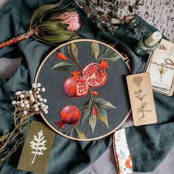 a cross - stitch project with pomegranates and other items on it