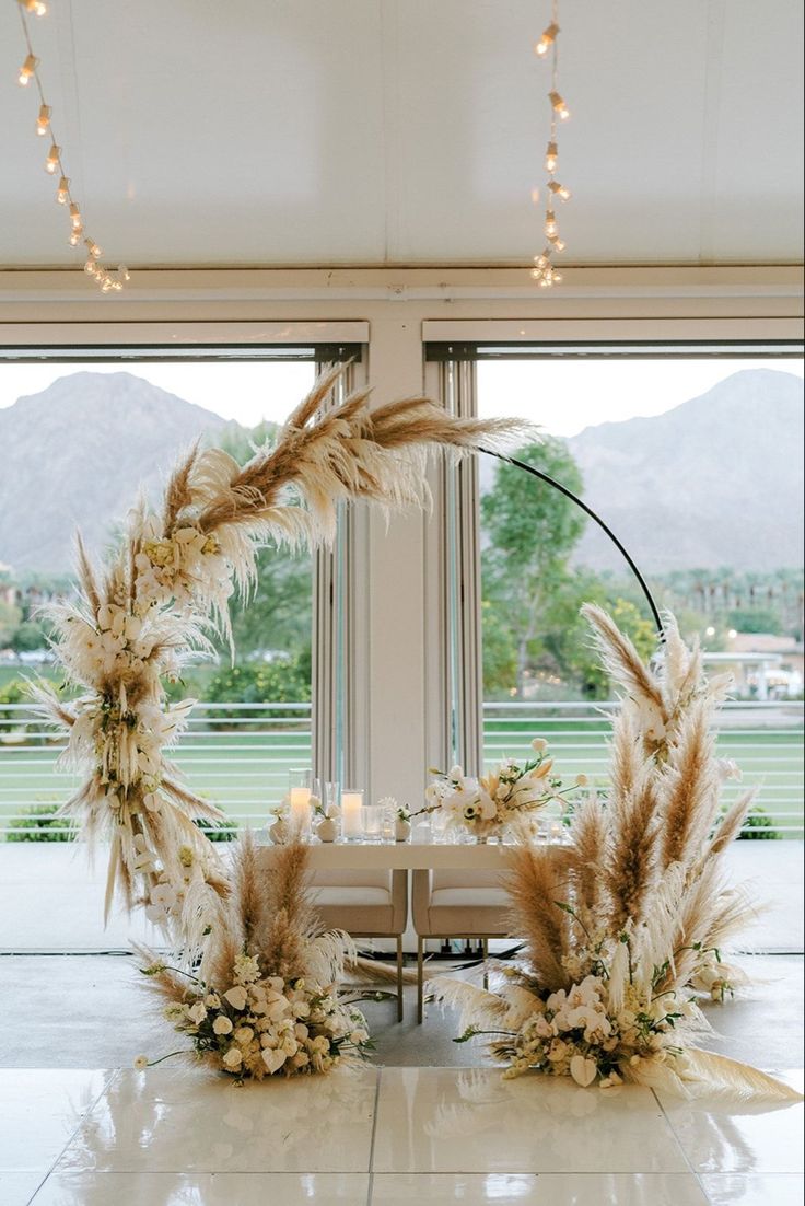 a table with flowers and candles in front of large windows