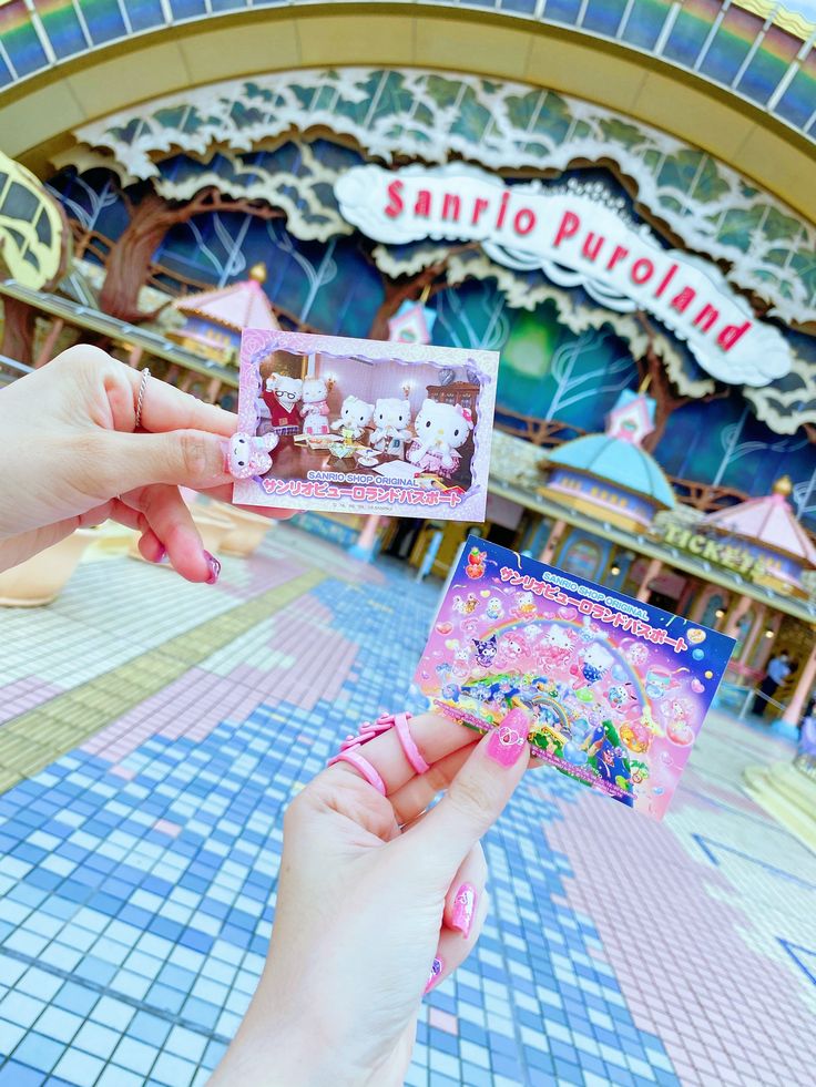 a person holding up a hello kitty card in front of a building with a sign that says sanrio purolad