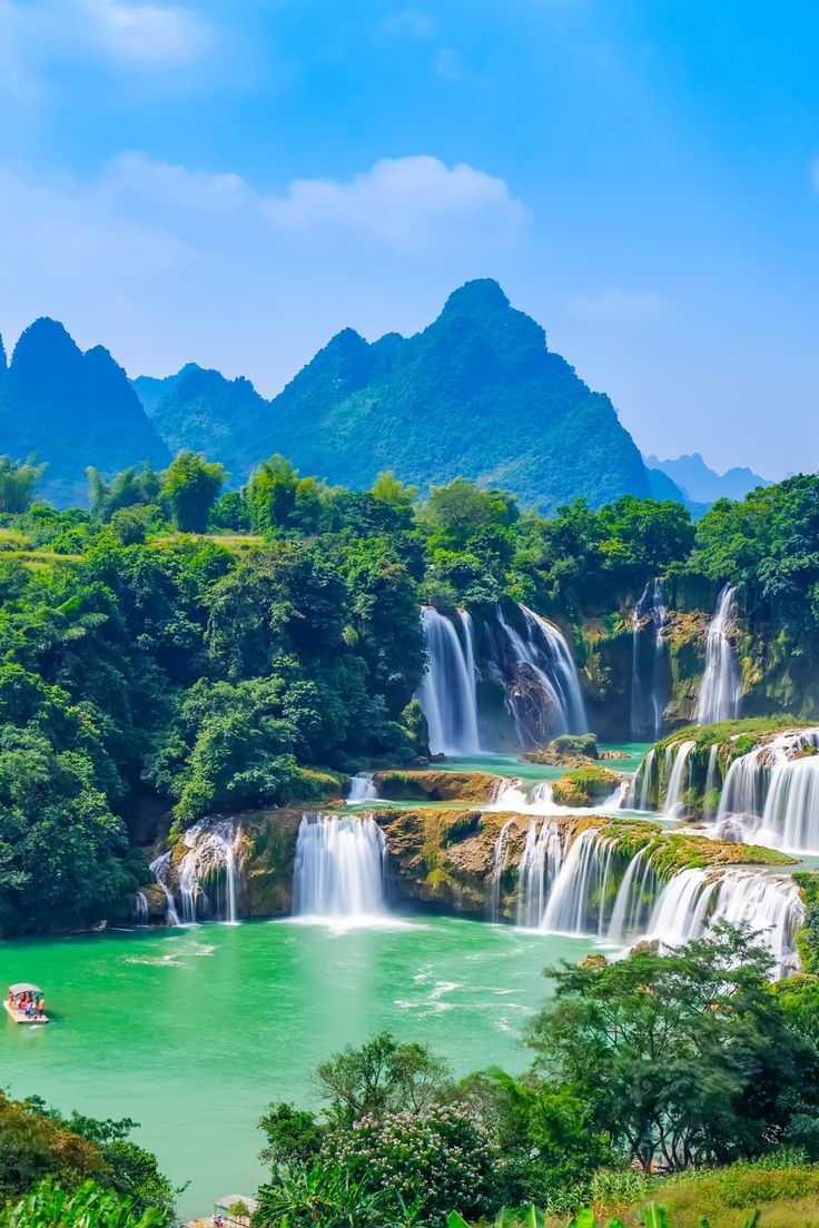 the beautiful waterfalls are surrounded by lush green trees and water, with boats in the foreground