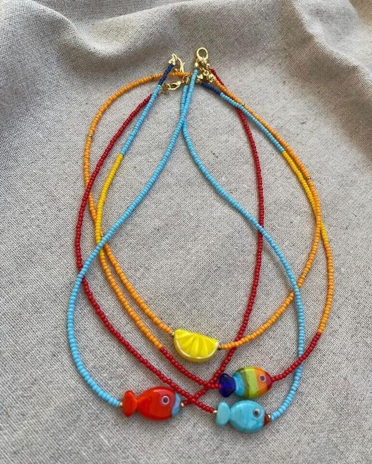 multicolored beaded bracelets with fish charms on top of a white cloth