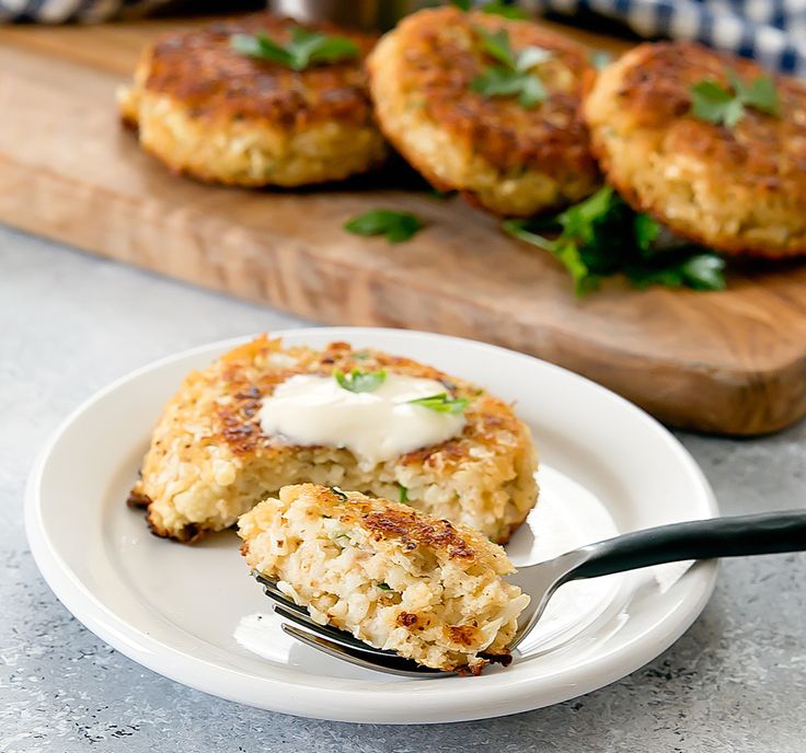 crab cakes on a white plate with a fork in the foreground and another dish behind it