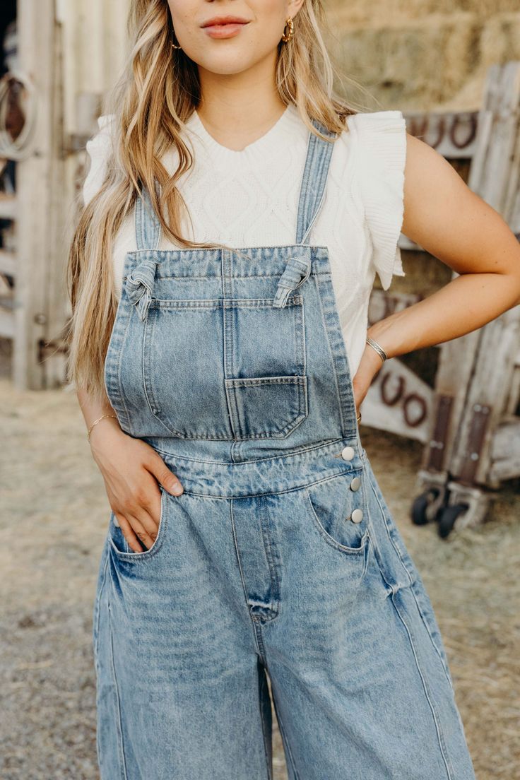 Get ready to rock the denim trend with The Myles Overalls! These barrel jean overalls feature a loose fit and adjustable shoulder straps for ultimate comfort. Perfect for a western-inspired look, these overalls are a must-have for anyone. Courtney is wearing size small paired with The Susana Top and American Cowgirl Trucker Denim Blue Overalls With Adjustable Straps, Fall Shortalls With Bib Front And Pockets, Medium Wash Denim Jumpsuit With Adjustable Straps, Utility Style High Rise Medium Wash Overalls, Utility High Rise Medium Wash Overalls, Medium Wash Denim Overalls With Adjustable Straps, Trendy Denim Jumpsuit With Adjustable Straps, Fall Medium Wash Bib Front Denim Jumpsuit, Medium Wash Overall Shortalls With Suspenders