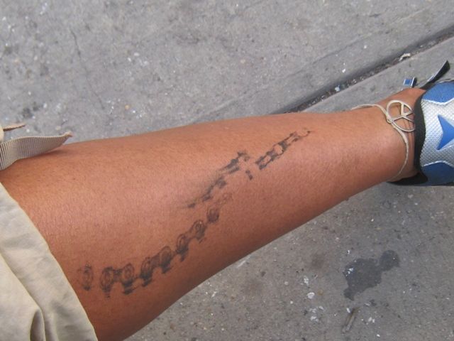 a person with a tattoo on their arm is standing in front of the street and has his leg wrapped up