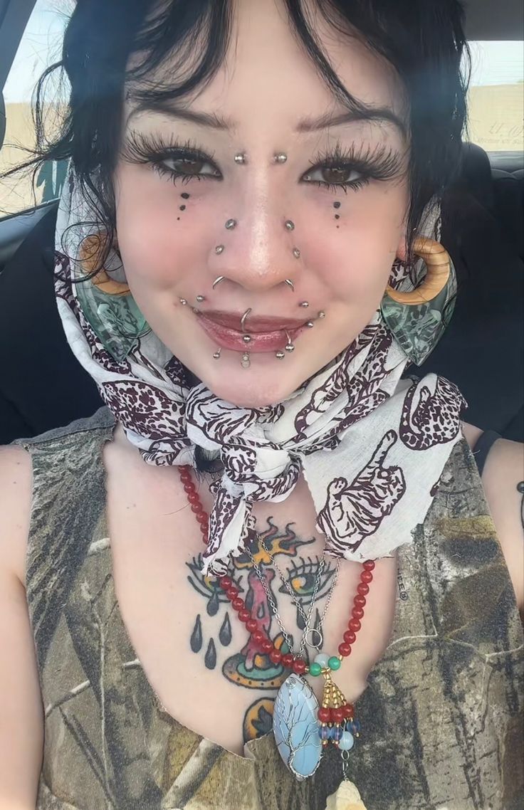 a woman with tattoos on her face and neck in the back seat of a car