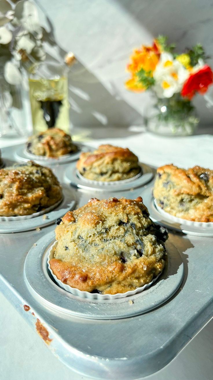 several muffins sitting on top of a pan next to a vase with flowers