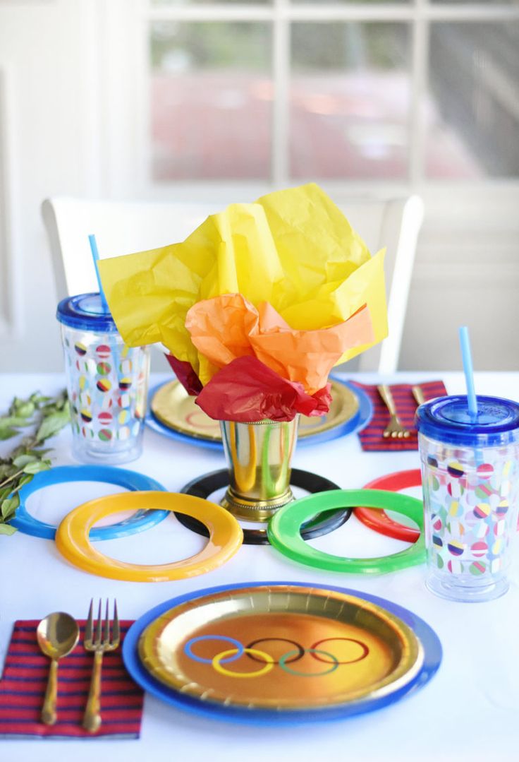 an olympic themed table setting with plates, cups and napkins