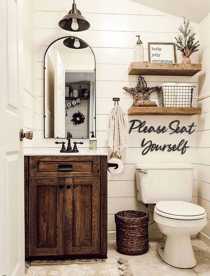 a white toilet sitting next to a wooden cabinet in a bathroom under a large mirror