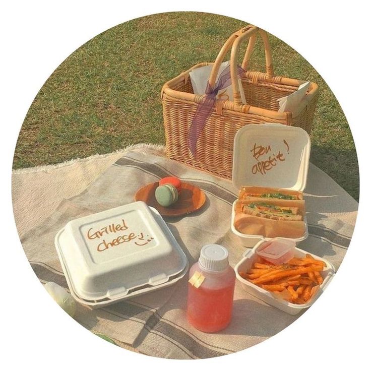 a picnic table with sandwiches, carrots and condiments on it in front of a basket