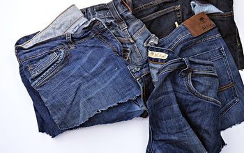 several pairs of jeans sitting on top of each other, with one folded up and the other unbuttoned