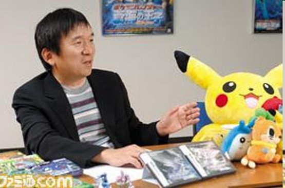 a man sitting at a desk in front of a stuffed pikachu and other toys