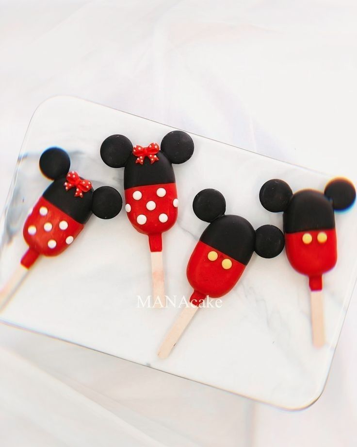 three mickey mouse lollipops are on a tray