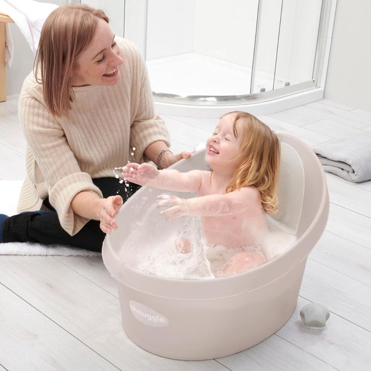 a mother and her daughter are playing in the bathtub with foamy bubbles on the floor