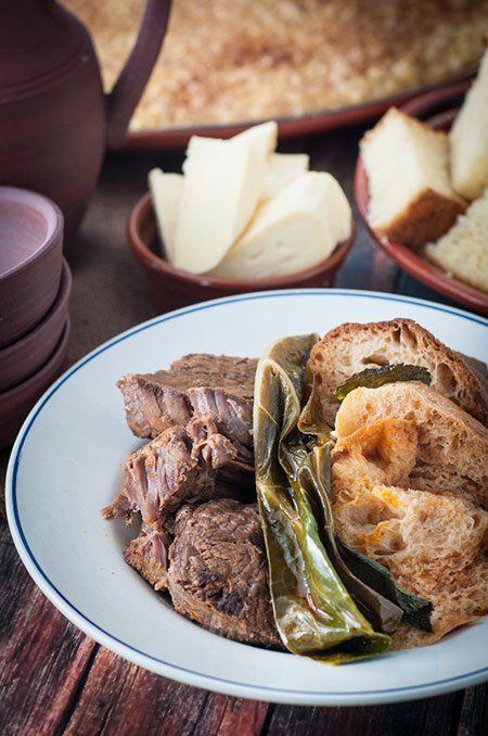 a white plate topped with meat and vegetables next to other foods on top of a wooden table