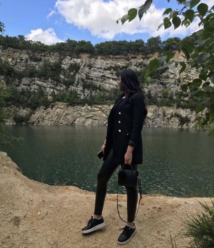 a woman standing on top of a hill next to a lake