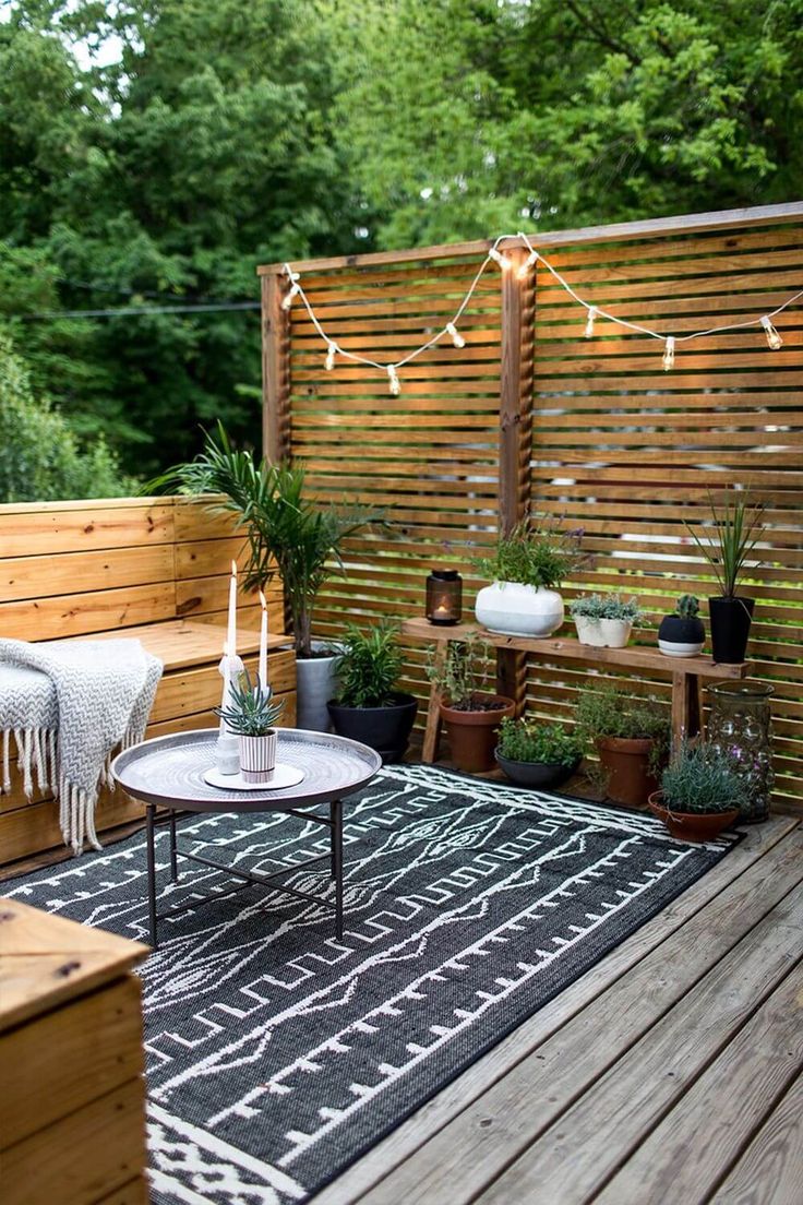 an outdoor patio with potted plants and lights strung over the top of the fence