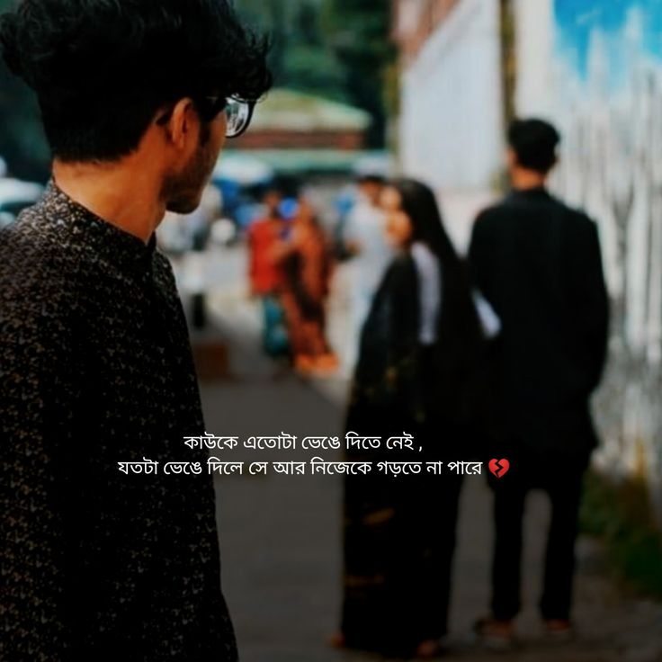 a man standing on the side of a road next to a wall with writing on it